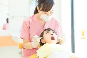 女の子が診療台にのって歯科治療を受けている写真