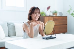 鏡で口の中を確認する女性の写真
